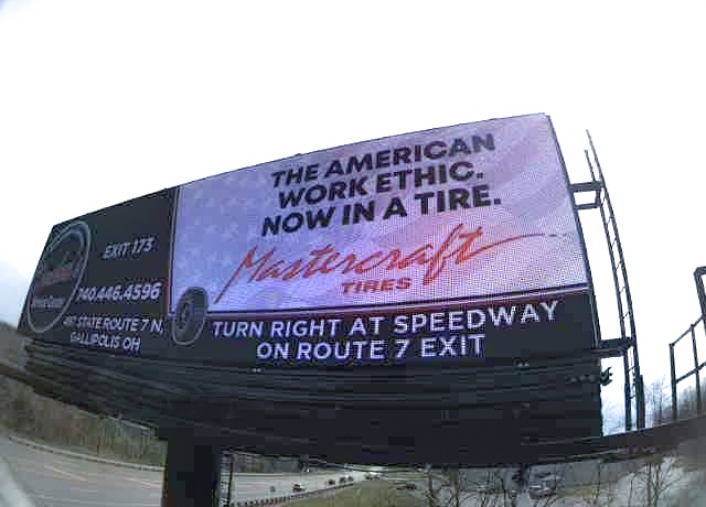 Digital billboard for tire shop shown from close up with a freeway in the background.